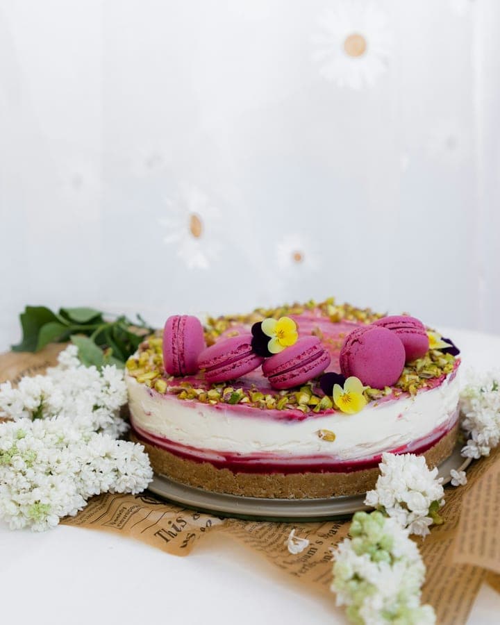 Raspberry cheesecake topped with pink macarons and edible flowers
