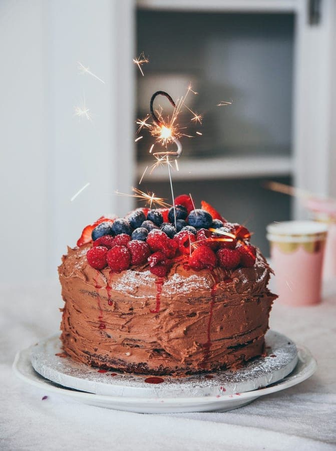 Chocolate cake topped with fresh berries and a sparkler